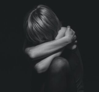 grayscale photo of a person hugging self