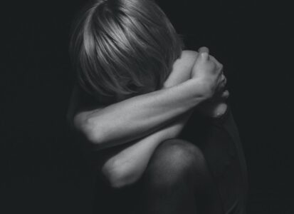 grayscale photo of a person hugging self