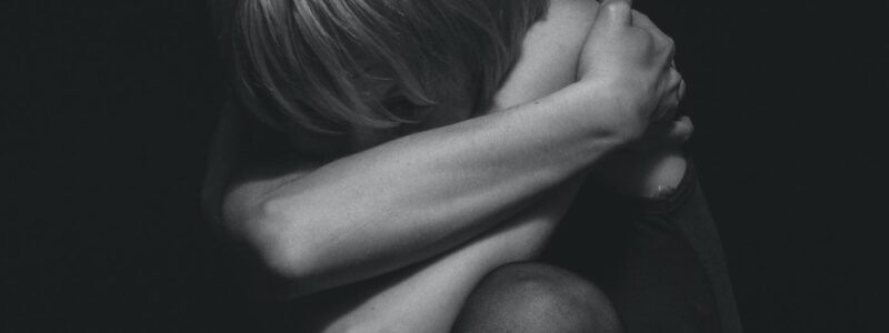 grayscale photo of a person hugging self